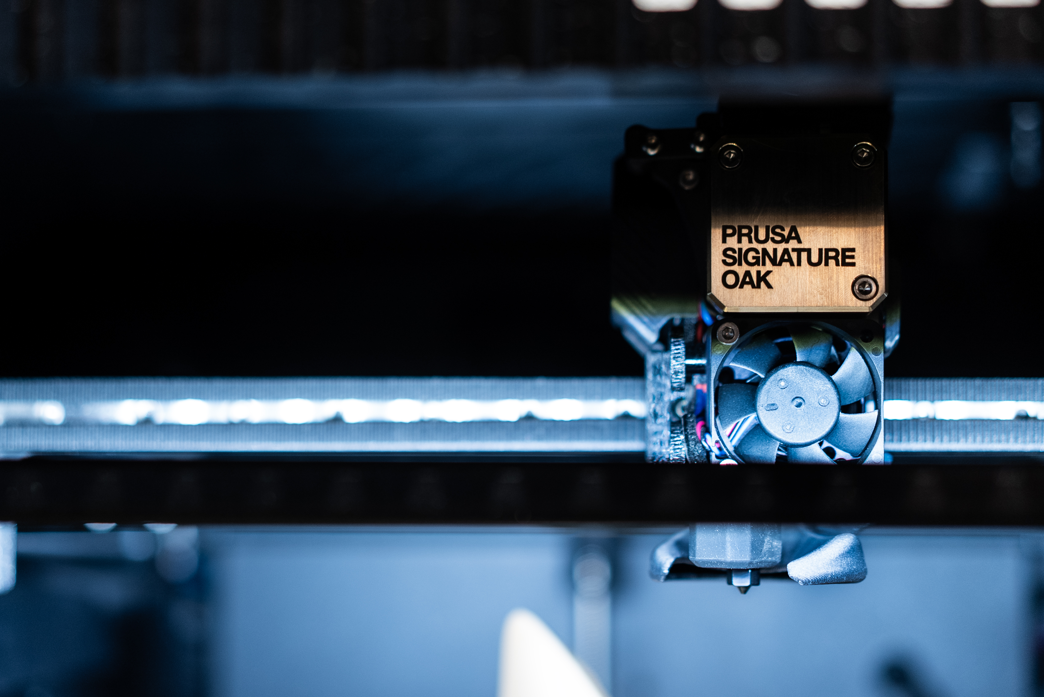 Boczne drzwiczki drukarki Prusa Signature Oak otwierają się, odsłaniając wbudowany uchwyt na szpulę filamentu